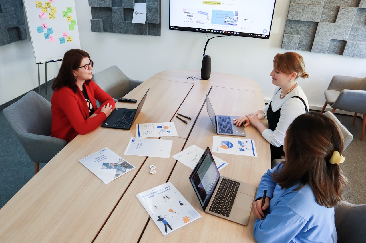 a group of people sitting around a table with laptops